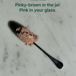 Unedited photo of Gut Ritual+ powder on a spoon: pinky-brown in the jar, turns pink in water