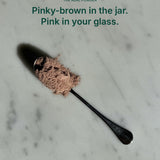 Unedited photo of Gut Ritual+ powder on a spoon: pinky-brown in the jar, turns pink in water